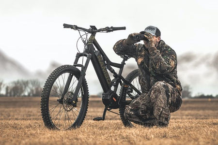 Hunter with binoculars and his Rambo electric hunting bike looking for wild game to hunt.